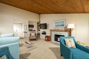 A living room with a fireplace, a television, and a bookshelf. - Above the Waves - Views! Pool! Beach! Tennis! (Solana Beach)