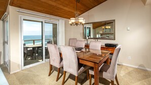 A dining area with a wooden table and chairs, a chandelier, and a large mirror on the wall.