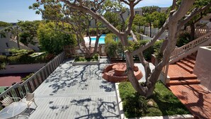 A wooden deck with a circular brick planter, a white railing, and a view of a residential area with houses and trees.