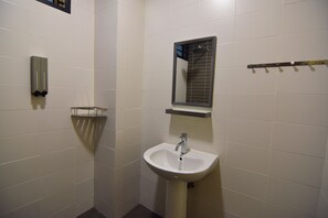 Un baño con paredes de azulejos blancos, un lavamanos blanco, un espejo y un perchero para toallas.