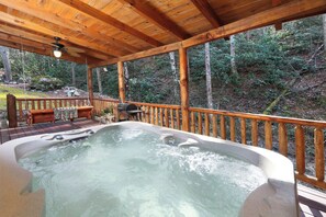 A hot tub on a wooden deck with a wooden railing, surrounded by a forested area. - Wood Burning Fireplace | Secluded | Hot Tub | Wifi | Fireplace (SEVIERVILLE)