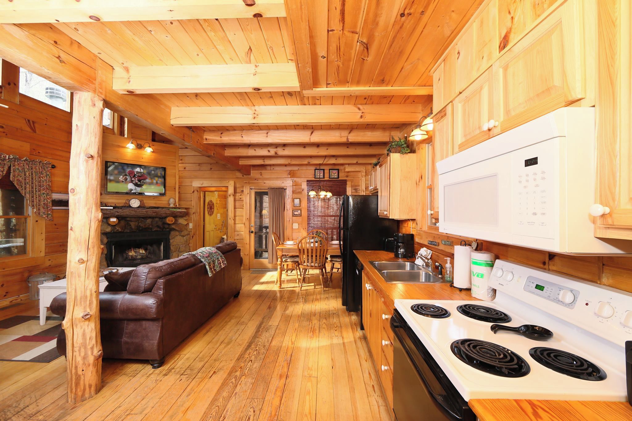 Interior de una cabaña de madera con sala de estar, cocina y comedor.