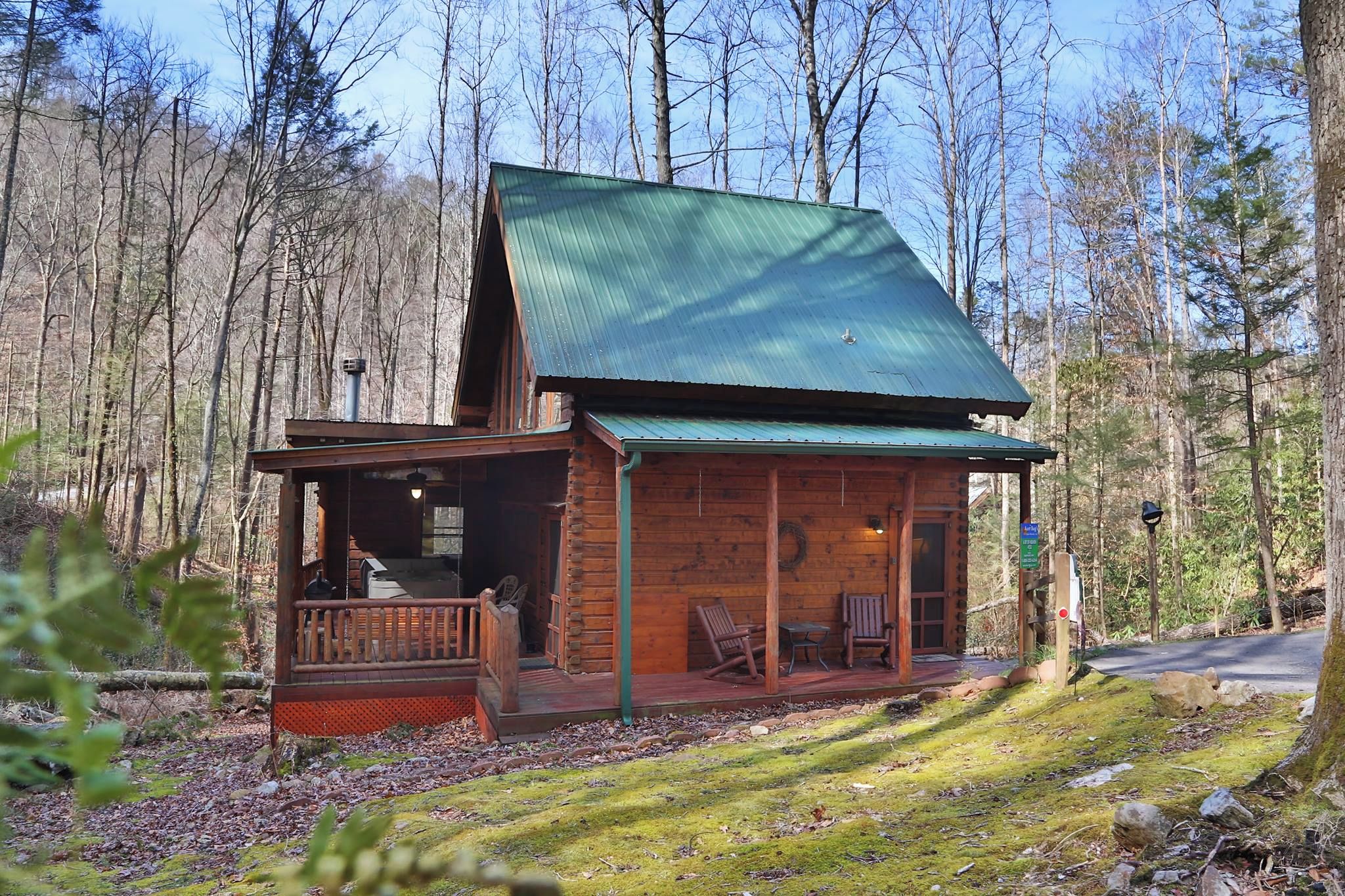 Eine rustikale Holzhütte mit Veranda und Sitzbereich, umgeben von einem Wald.