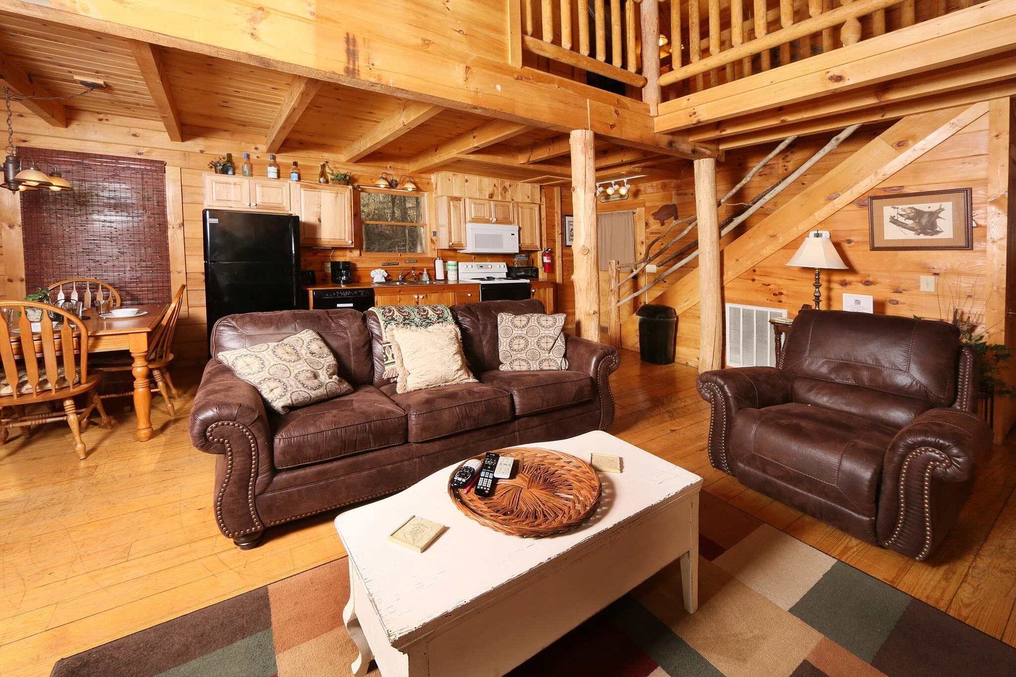 A cozy log cabin interior with a living room, dining area, and kitchen.
