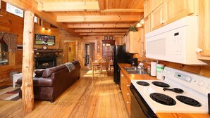 Een houten chalet van binnen met een woonkamer, keuken en eethoek.