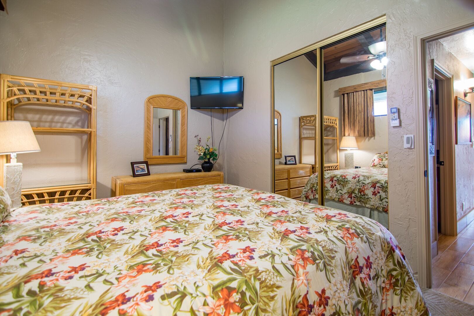 Une chambre à coucher avec un lit, une commode, une télévision et un grand miroir.