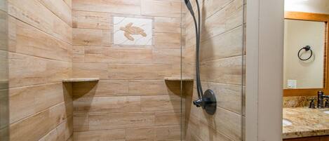 A shower with a wooden wall design, a towel rack, and a tiled artwork.