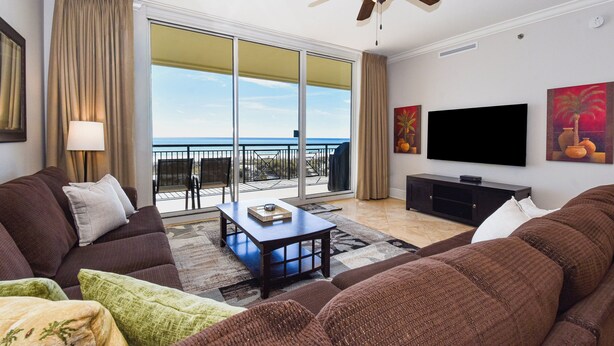 Un salon comprenant un canapé, une table basse, un téléviseur et un balcon avec vue sur l’océan.