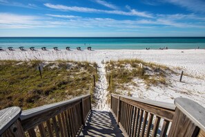 A wooden staircase leading to a beach with clear skies.