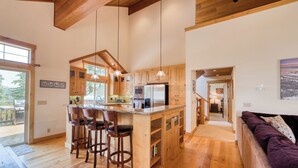 A spacious kitchen with wooden cabinets, a central island with bar stools, and pendant lighting.
