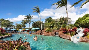 A clear pool with palm trees and a waterfall feature. - Lawai Beach 1401 Oceanfront By Suite Paradise (Koloa)