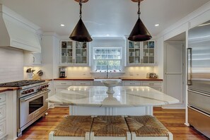 A modern kitchen with white cabinetry, a central island, a stove, and a refrigerator.