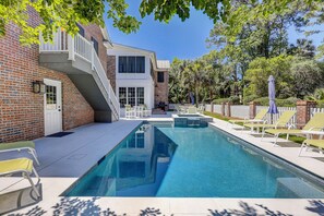 A swimming pool with a patio area, a brick building, and a white fence.