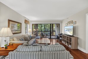 A spacious living room with a large sofa, a television, and a dining area with a table and chairs.