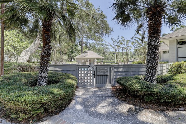 A gated entrance to a private pool area with a pathway leading to a building.