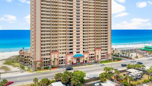 A tall hotel with multiple balconies, a beach view, and a parking area. - BEACHFRONT CONDO! 8TH FLOOR! FREE BEACH SERVICE (Panama City Beach)