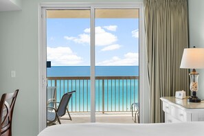 Enjoy the ocean view from the balcony, featuring a comfortable bed and seating area.