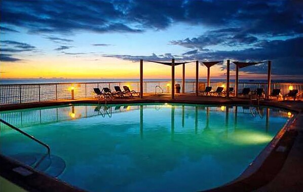 Ein Pool mit Liegestühlen und Blick auf den Sonnenuntergang.