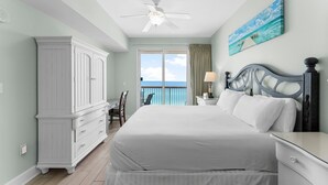 A bedroom with a large bed, a ceiling fan, a view of the ocean through a balcony door, and a white wardrobe. - BEACHFRONT CONDO! 8TH FLOOR! FREE BEACH SERVICE (Panama City Beach)