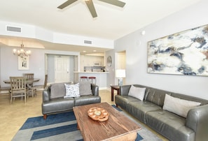 A living room with a sofa, coffee table, and a dining area with chairs and a table.