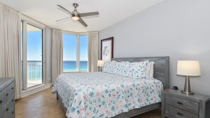 A bedroom with a bed, nightstand, and a ceiling fan. - Open Concept Beachfront Condo w/ Easy Beach Access in Central Destin! 🌴💙🌅 (Destin)