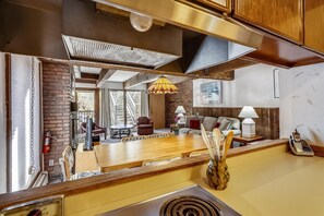 A kitchen with a wooden countertop, a stove, and a dining area with a table and chairs.