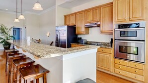 A modern kitchen with wooden cabinets, stainless steel appliances, and a granite countertop.
