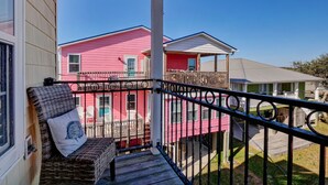 A balcony with wicker furniture and a view of neighboring houses.