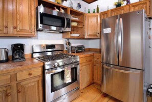 A kitchen with wooden cabinets, stainless steel appliances including a microwave, stove, oven, and refrigerator. - Pooches Paradise, Elk Ave location! Dog friendly! (Crested Butte)
