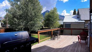 Une terrasse en bois avec un barbecue, des sièges d’extérieur et une vue sur la montagne.