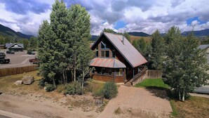 Une cabane au toit en pente, entourée d’arbres, avec une montagne en toile de fond.