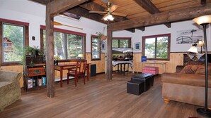 Un vaste espace de vie doté d’un plancher en bois, d’une table à manger et d’un coin salon avec un canapé et un pouf.