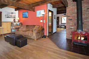 A cozy living room with a leather sofa, wooden flooring, a fireplace, and a bookshelf. - Pooches Paradise, Elk Ave location! Dog friendly! (Crested Butte)