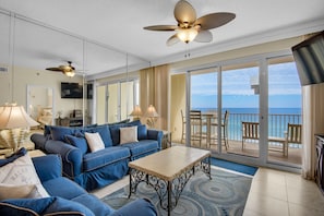 Relax in this stylish living area with a sofa, coffee table, and TV, plus a sliding door leading to a balcony with ocean views.