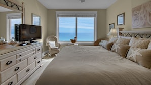 A bedroom with a large bed, a television on a dresser, a ceiling fan, and a view of the ocean through a window. - 🌴Beach Chairs~Gulf Views~2 Pools~Leeward Key 905~Suite Sea-Cret🌴 (Miramar Beach)