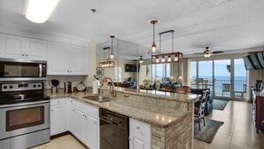 A modern kitchen with white cabinets, stainless steel appliances, and a large island. - 🌴Beach Chairs~Gulf Views~2 Pools~Leeward Key 905~Suite Sea-Cret🌴 (Miramar Beach)