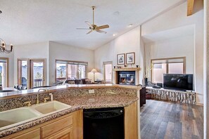 Enjoy cooking in this well-equipped kitchen with a dishwasher and adjacent living area featuring a fireplace and flat-screen TV.