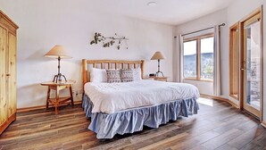 Un dormitorio con cama de madera, dos mesitas de noche, una ventana con cortinas y vistas al exterior.