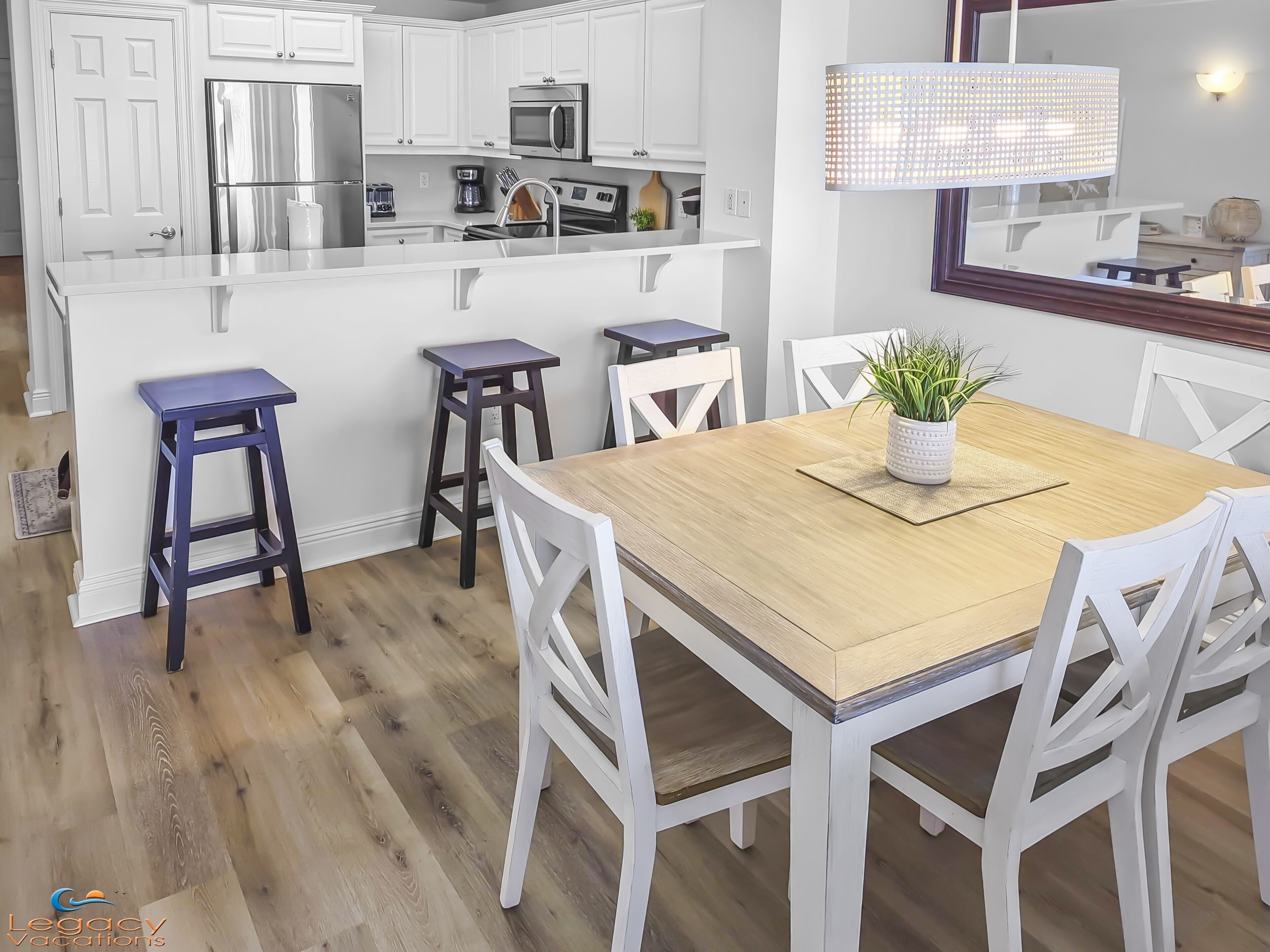 Une cuisine moderne avec des meubles blancs, une table à manger en bois et des tabourets de bar.