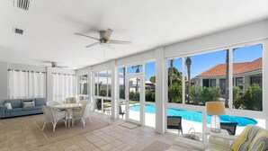 A spacious indoor area with a pool view, white furniture, and a ceiling fan. - SHORT WALK TO BEACH!! PRIVATE POOL! (Destin)