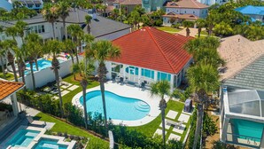 A residential area with a swimming pool surrounded by palm trees and houses with red-tiled roofs. - SHORT WALK TO BEACH!! PRIVATE POOL! (Destin)