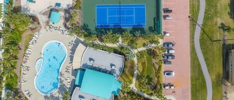 Oversigtsbillede af et resort med swimmingpool, tennisbaner og parkeringsplads.