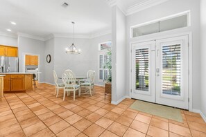 A kitchen with wooden cabinets, a dining table with chairs, and a pendant light. - SHORT WALK TO BEACH!! PRIVATE POOL! (Destin)