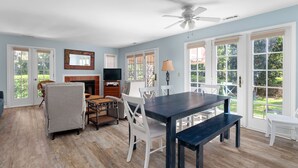 A spacious living room with a fireplace, a television, and a dining area with a table and chairs.