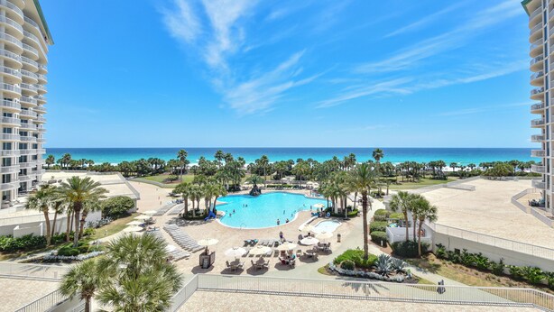 A resort with a central swimming pool, palm trees, and a view of the ocean. - Updated, modern, beachfront condo w/private balcony! 🌴 (Destin)