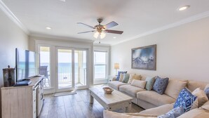 A spacious living room with a large sofa, a coffee table, and a ceiling fan.