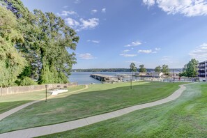 A grassy area with a walking path, a dock, and a building with a view of the water.