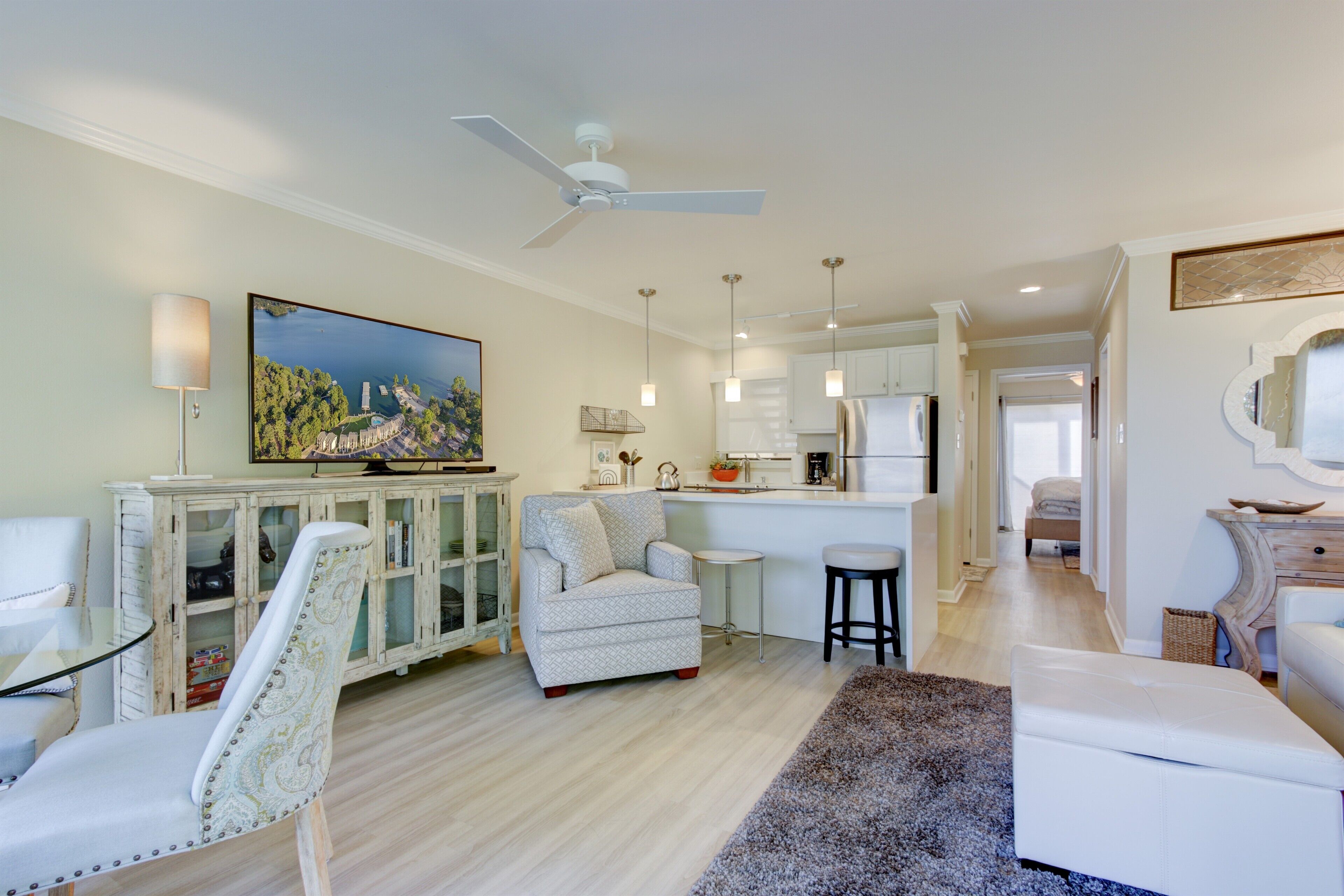 A spacious living area with a dining table, a sofa, a kitchen in the background, and a ceiling fan.