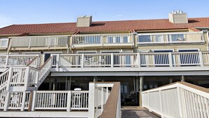 Ein mehrstöckiges Gebäude mit rotem Ziegeldach, weißen Geländern und einer Holzterrasse.