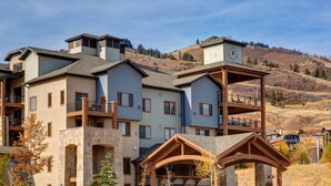 Un hotel a più piani con facciata in pietra, balconi e vista su un paesaggio collinare.